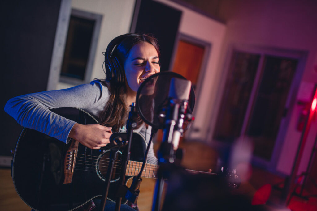 girl recording guitar and vocals in music studio