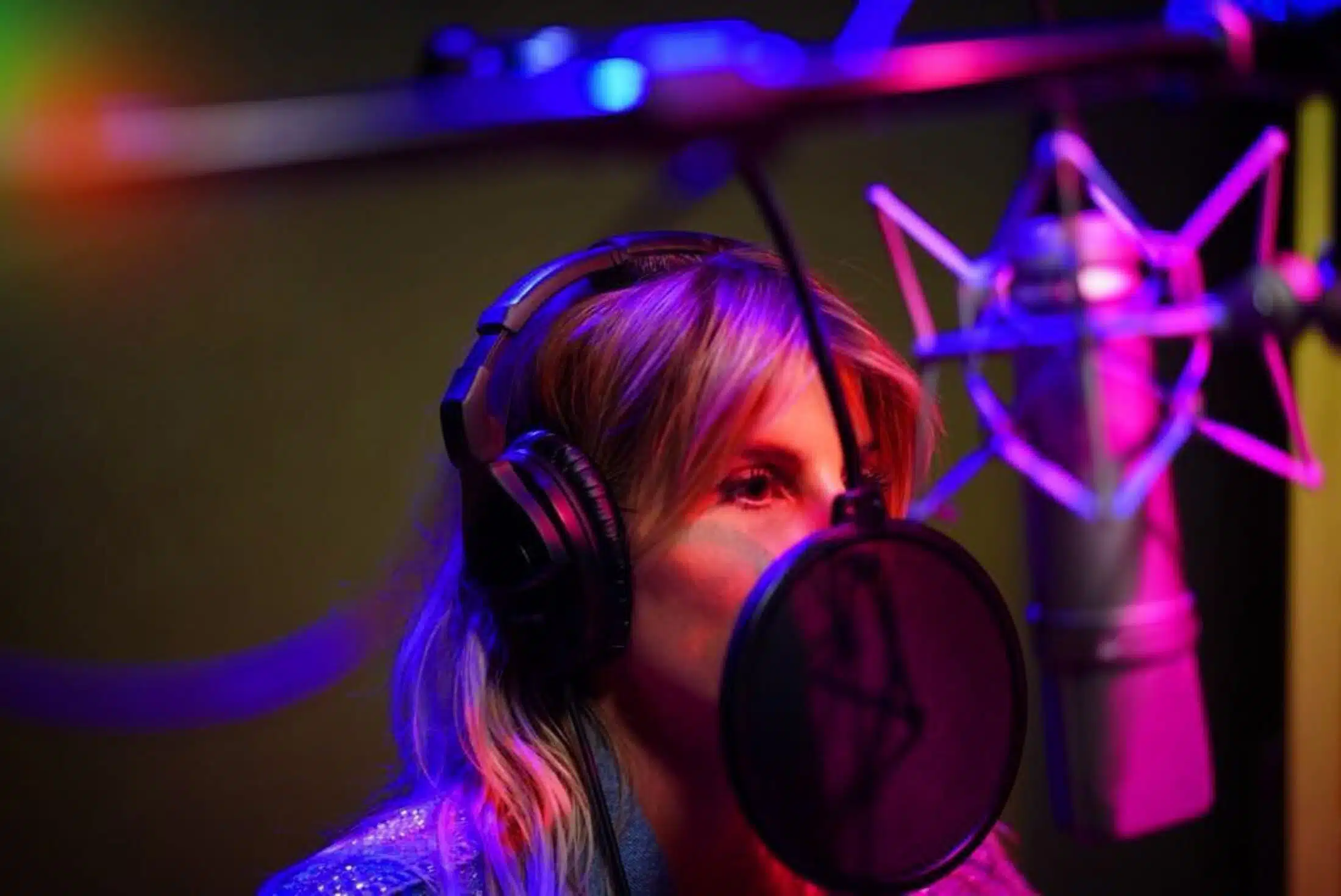 mujer grabando en cabina vocal de estudio
