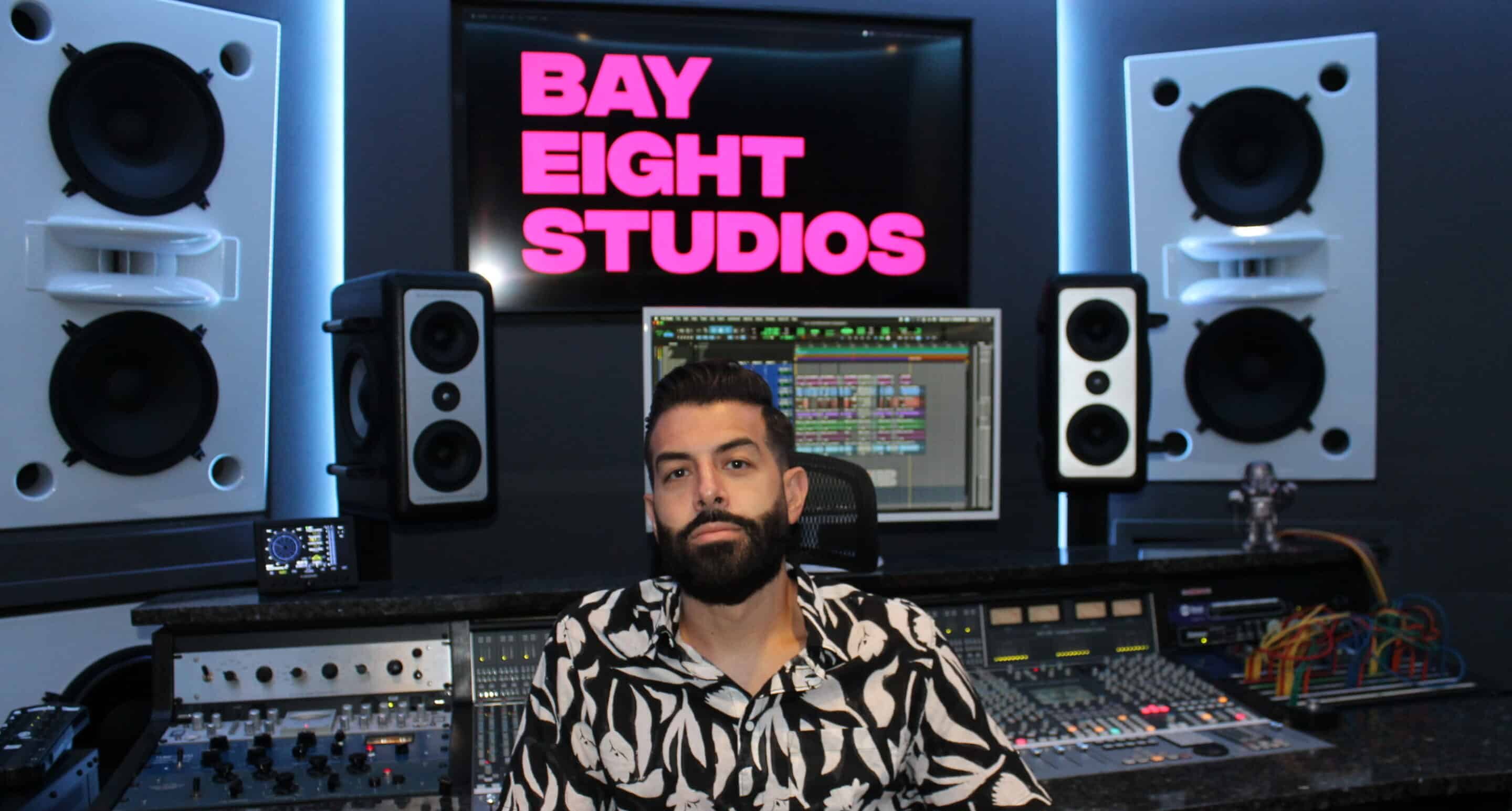 Matthew DeFreitas sitting in front of Bay Eight Recording Studios logo music studio rental