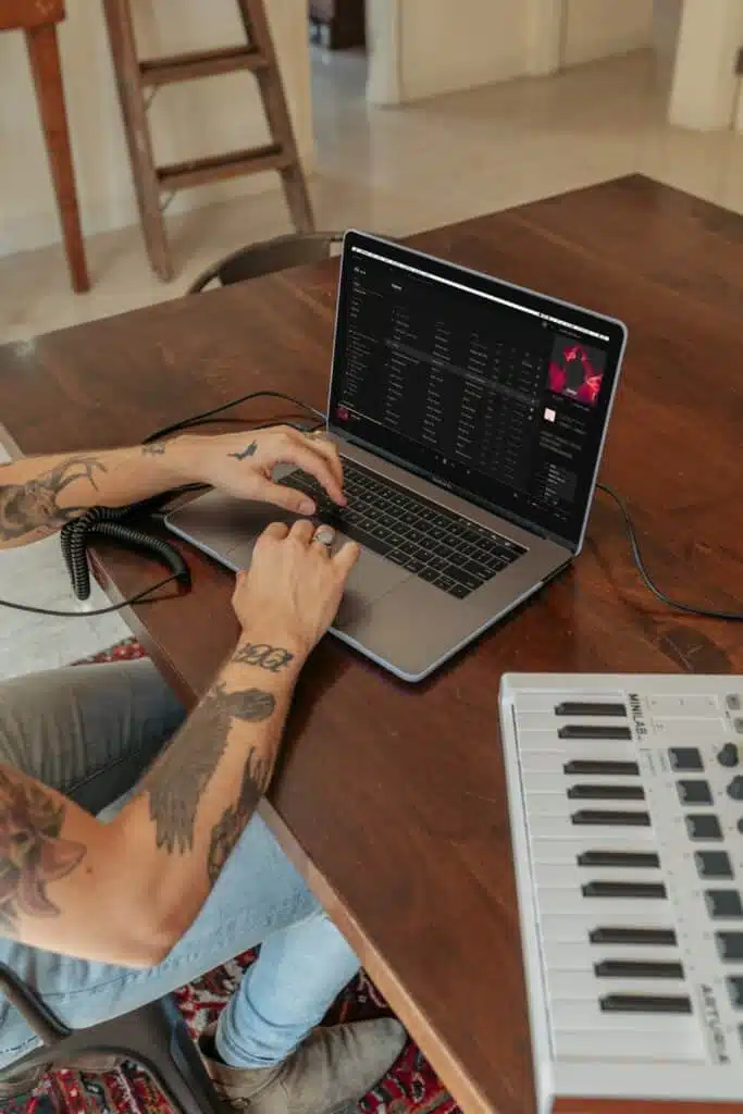 Tattooed person working on music online